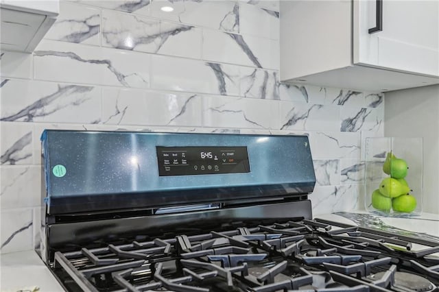 details featuring white cabinetry, tasteful backsplash, and gas range oven