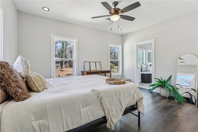 bedroom with connected bathroom, multiple windows, and dark wood-type flooring