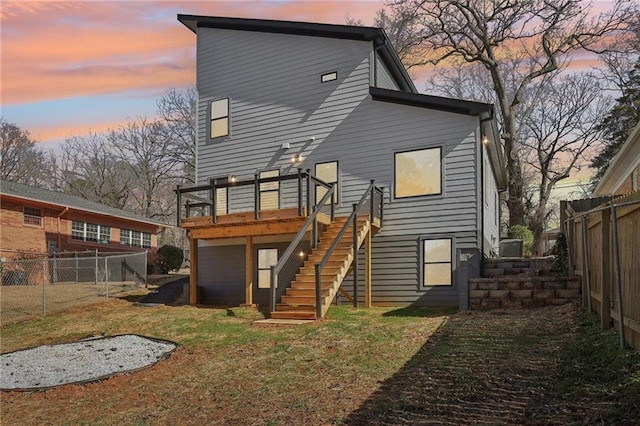 back house at dusk featuring a yard and a deck