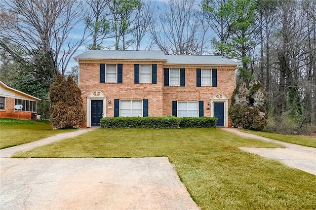 colonial-style house with a front yard, concrete driveway, and brick siding