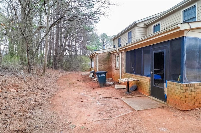 view of home's exterior featuring brick siding and a sunroom