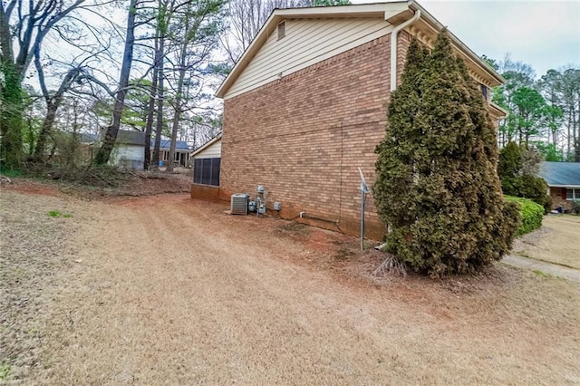 view of side of property featuring central AC and brick siding