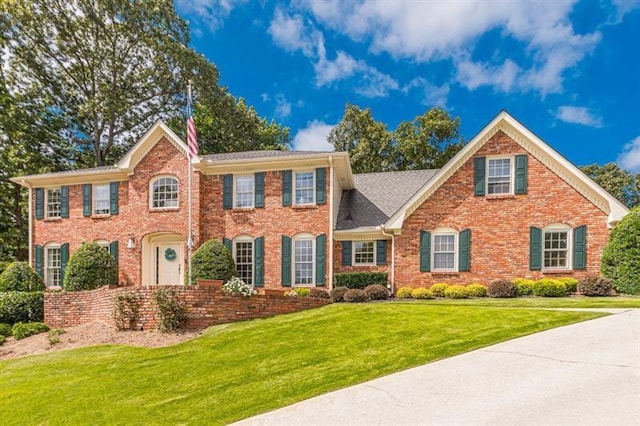 colonial home with brick siding and a front yard