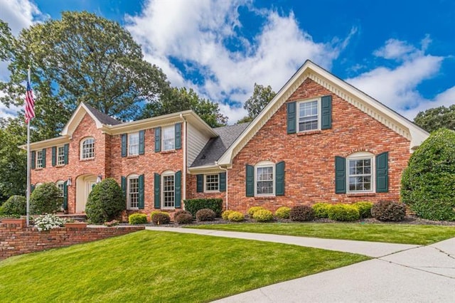 colonial house featuring brick siding and a front yard