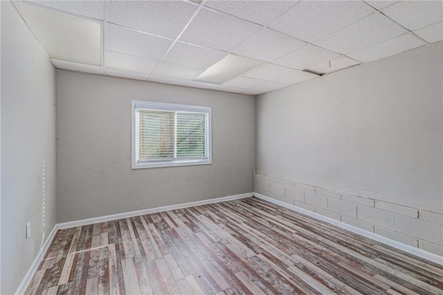 unfurnished room featuring a drop ceiling and light wood-type flooring