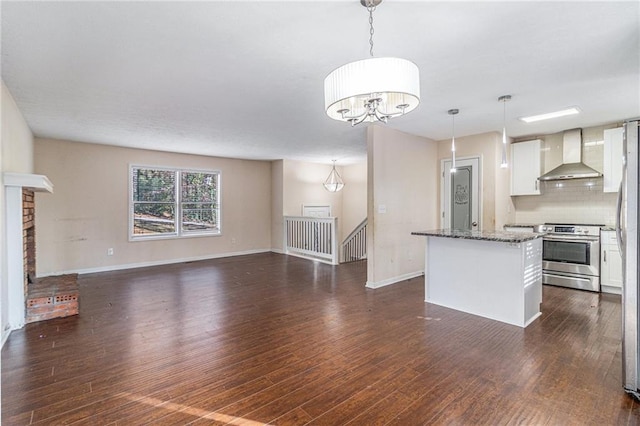 kitchen featuring stainless steel electric stove, decorative light fixtures, white cabinetry, and wall chimney range hood