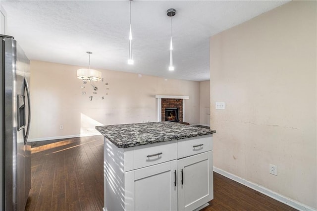 kitchen featuring hanging light fixtures, stainless steel fridge with ice dispenser, dark hardwood / wood-style floors, dark stone counters, and white cabinets