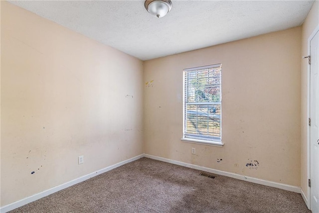 carpeted empty room with a textured ceiling