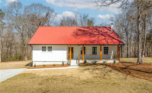 view of front of home with metal roof, a porch, a front lawn, and board and batten siding