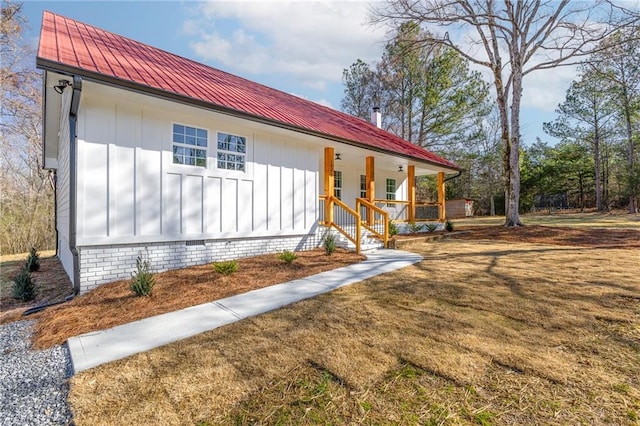 view of side of home featuring metal roof, a porch, board and batten siding, and a lawn