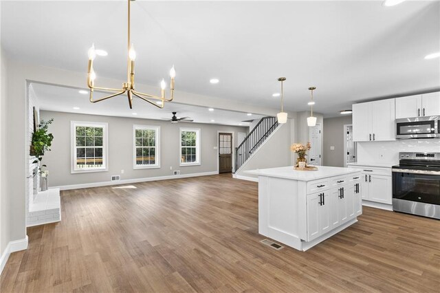 kitchen with visible vents, white cabinets, appliances with stainless steel finishes, open floor plan, and wood finished floors