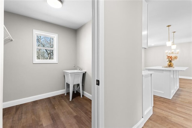 laundry room featuring light wood-style floors, a sink, and baseboards