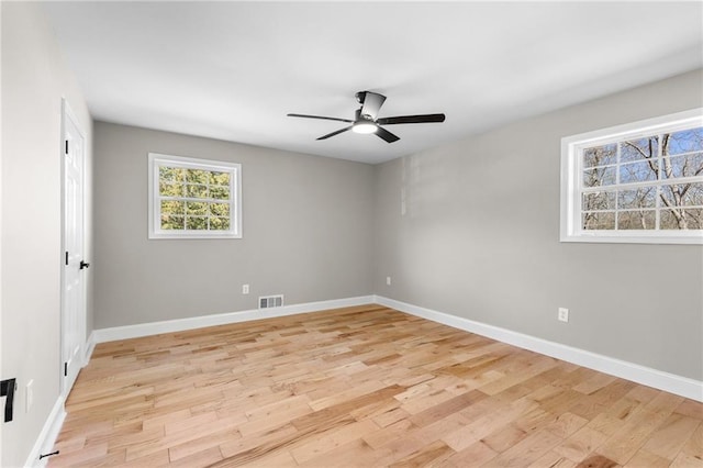 spare room featuring a ceiling fan, baseboards, visible vents, and light wood finished floors