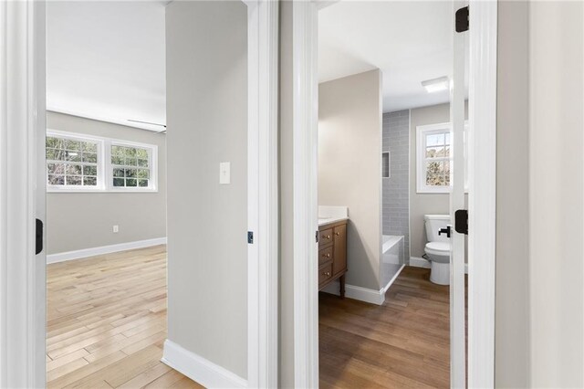 hall with light wood-style floors and baseboards