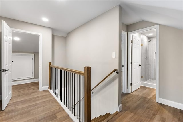 hall with baseboards, an upstairs landing, and wood finished floors