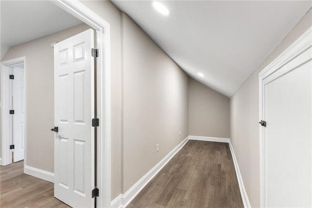 hallway featuring lofted ceiling, wood finished floors, and baseboards