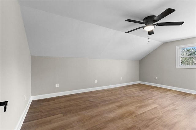 additional living space with vaulted ceiling, wood finished floors, and baseboards