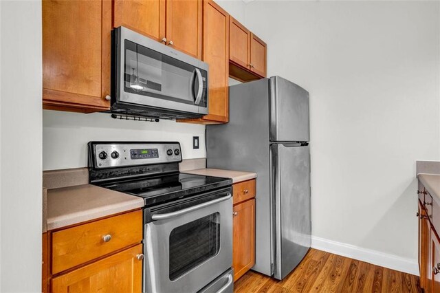 502 SW Pryor St SW Unit 325, Atlanta, GA 30312 - kitchen with appliances with stainless steel finishes, light wood-style floors, baseboards, brown cabinets, and light countertops