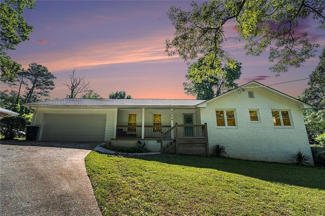 single story home featuring covered porch, an attached garage, a lawn, and driveway