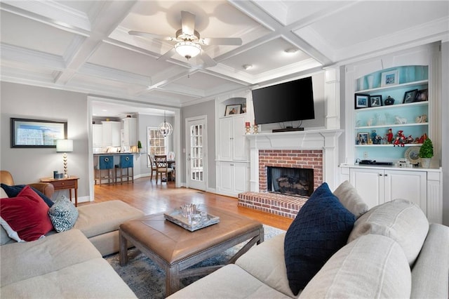 living room featuring a brick fireplace, beam ceiling, coffered ceiling, and light hardwood / wood-style flooring