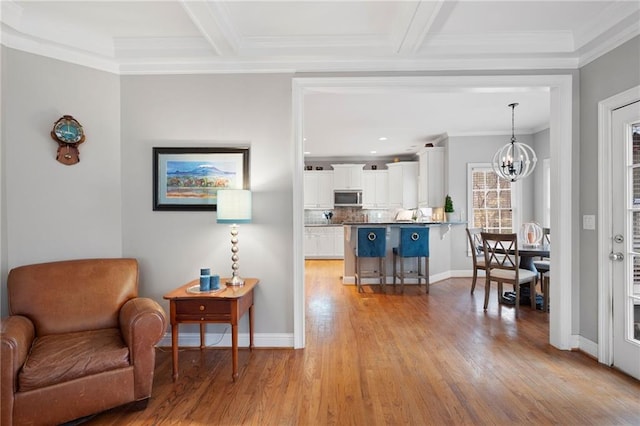 kitchen featuring white cabinetry, pendant lighting, light wood-type flooring, a breakfast bar area, and ornamental molding