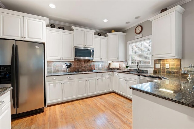 kitchen featuring white cabinets, light wood-type flooring, ornamental molding, and stainless steel appliances