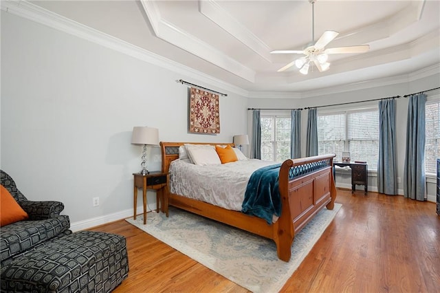 bedroom featuring hardwood / wood-style floors, ceiling fan, a raised ceiling, and crown molding