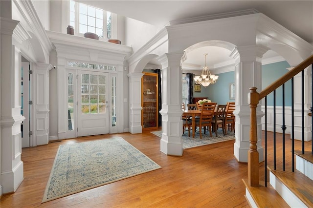 foyer with plenty of natural light, light hardwood / wood-style floors, a notable chandelier, and ornamental molding