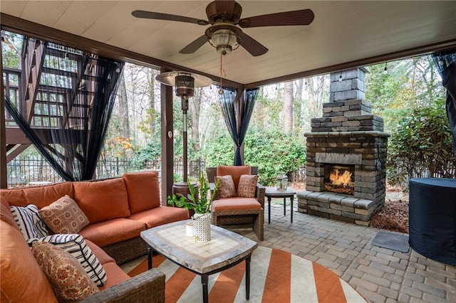 sunroom / solarium featuring plenty of natural light, ceiling fan, and an outdoor stone fireplace