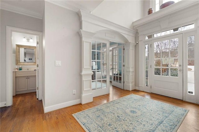 doorway with sink, decorative columns, crown molding, and light hardwood / wood-style flooring