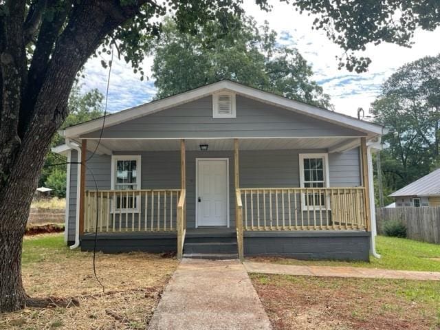 bungalow-style house featuring covered porch and a front yard