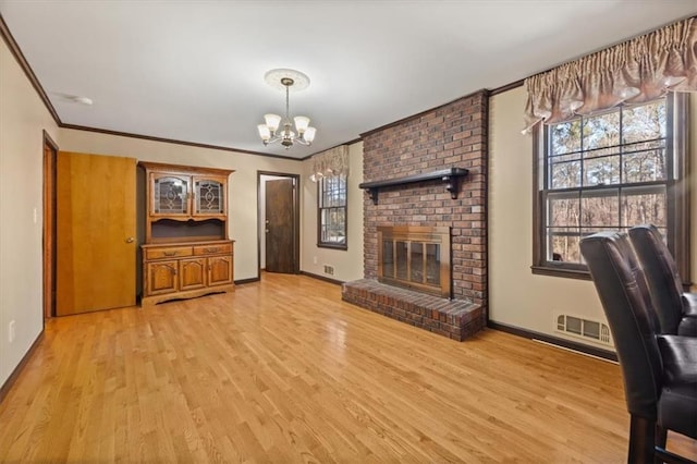 living room featuring a chandelier, a brick fireplace, ornamental molding, and light hardwood / wood-style floors