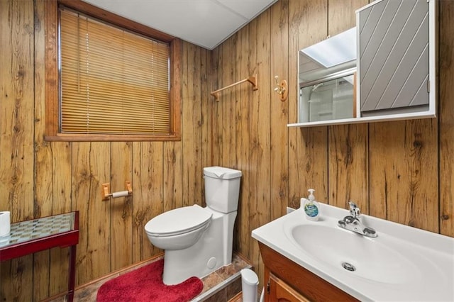 bathroom with toilet, wood walls, and vanity