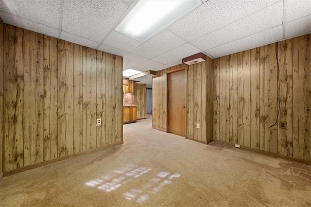 basement featuring a drop ceiling, wood walls, and carpet flooring