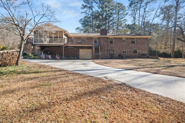 rear view of house with a lawn, a sunroom, and a garage