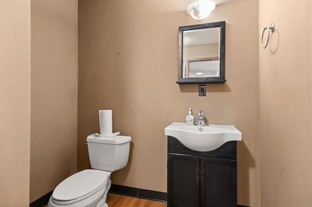 bathroom with toilet, vanity, and wood-type flooring