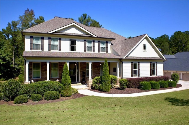 view of front of house with covered porch, a front lawn, and roof with shingles