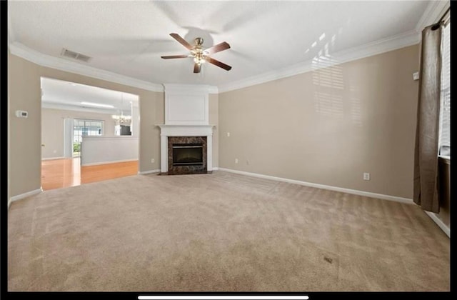 unfurnished living room with crown molding, a high end fireplace, light carpet, and ceiling fan with notable chandelier