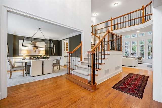 stairway with crown molding, a towering ceiling, and hardwood / wood-style flooring