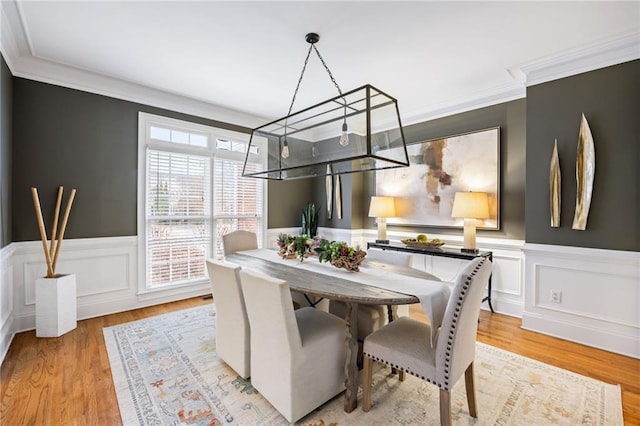 dining space with ornamental molding and light hardwood / wood-style floors