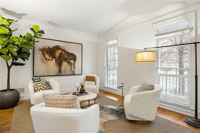 living area with hardwood / wood-style flooring, vaulted ceiling, and ornamental molding