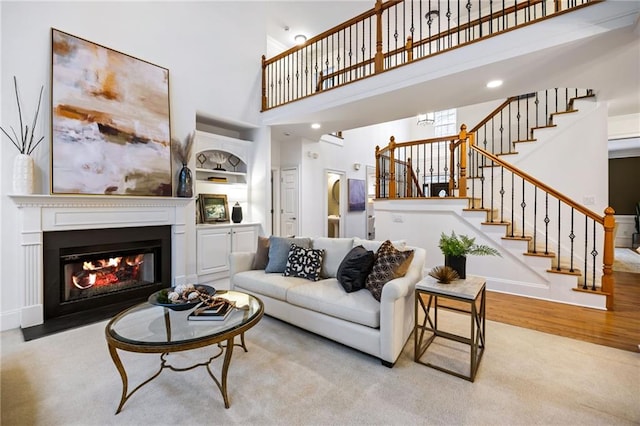 living room with a towering ceiling and light hardwood / wood-style flooring