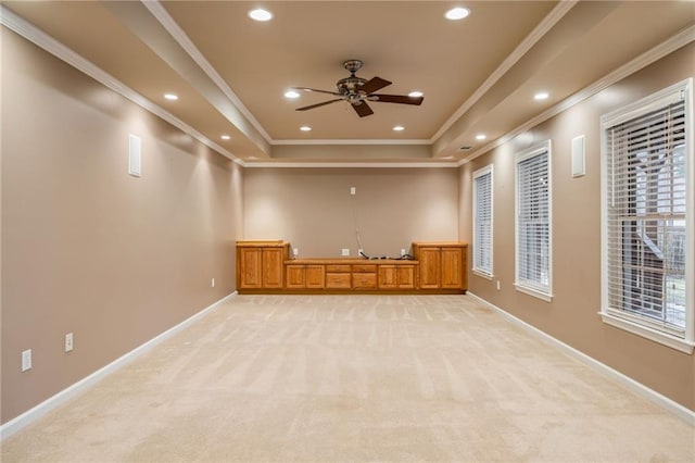 empty room with crown molding, ceiling fan, a raised ceiling, and light carpet