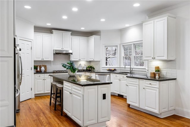 kitchen featuring sink, a center island, stainless steel appliances, light hardwood / wood-style floors, and white cabinets