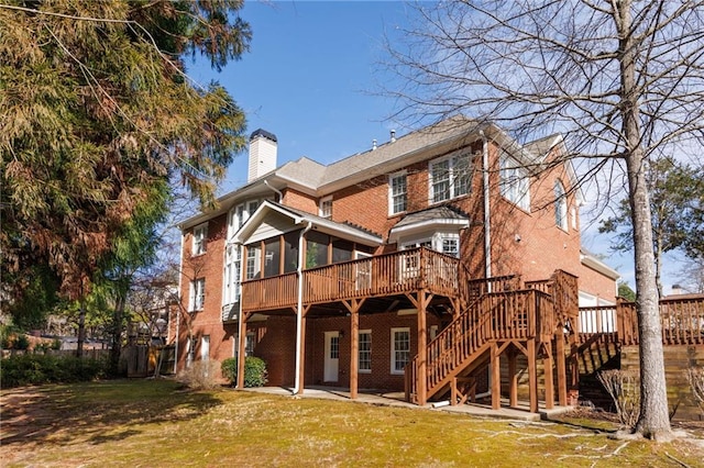 rear view of house with a sunroom, a yard, and a deck