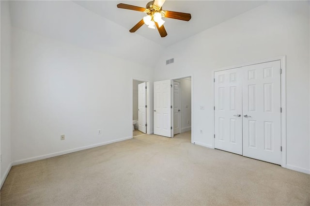 unfurnished bedroom featuring ensuite bath, ceiling fan, high vaulted ceiling, light colored carpet, and a closet