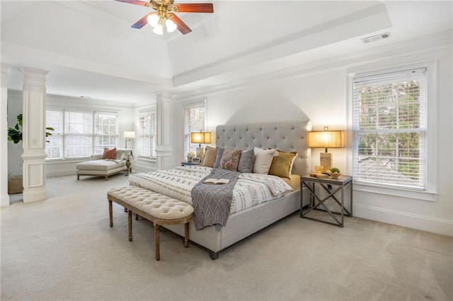 bedroom with a tray ceiling, carpet flooring, multiple windows, and ornate columns