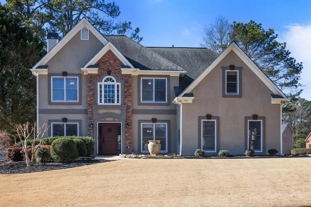 view of front of house featuring stucco siding, a chimney, and a shingled roof