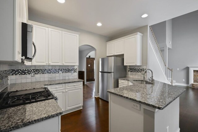 kitchen featuring a sink, dark wood-style flooring, gas range oven, and freestanding refrigerator