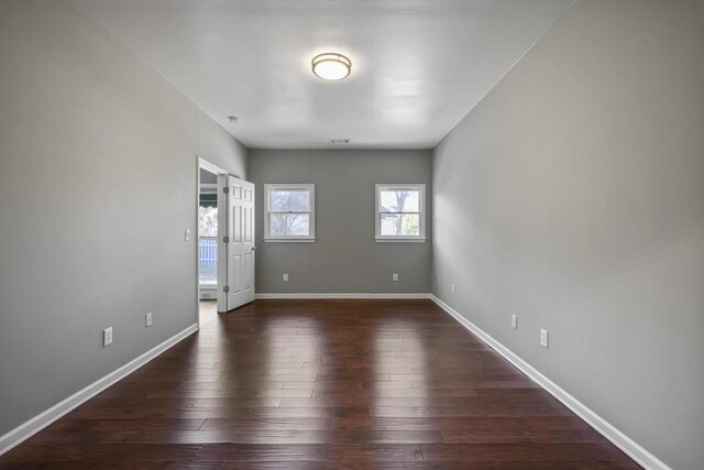 unfurnished room with baseboards and dark wood-style floors